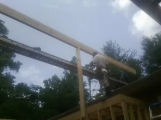Carpenter setting a ridge beam over a new addition frame — Ice Dam Removal by Roofing Brothers in Bowen