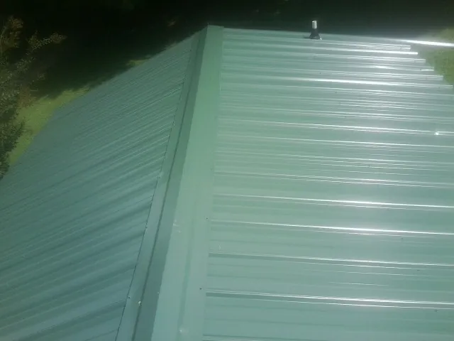 New green metal panels meeting at the ridge of a roof — Flat Roof Repair work by our crew in Bowen