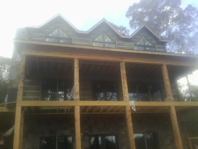 Dormers and porch framing on a large log home under construction — Roof Coating work by our crew in Bowen