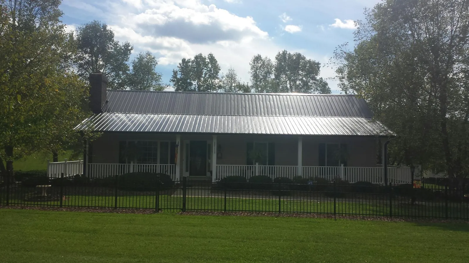 Gray metal roof on a brick ranch with a full width front porch — Gutter Guard Installation work by our crew in Bowen